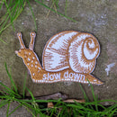 Iron-on patch | slow down snail - brown 1.6" x 2.6": Patch attached to backer card
